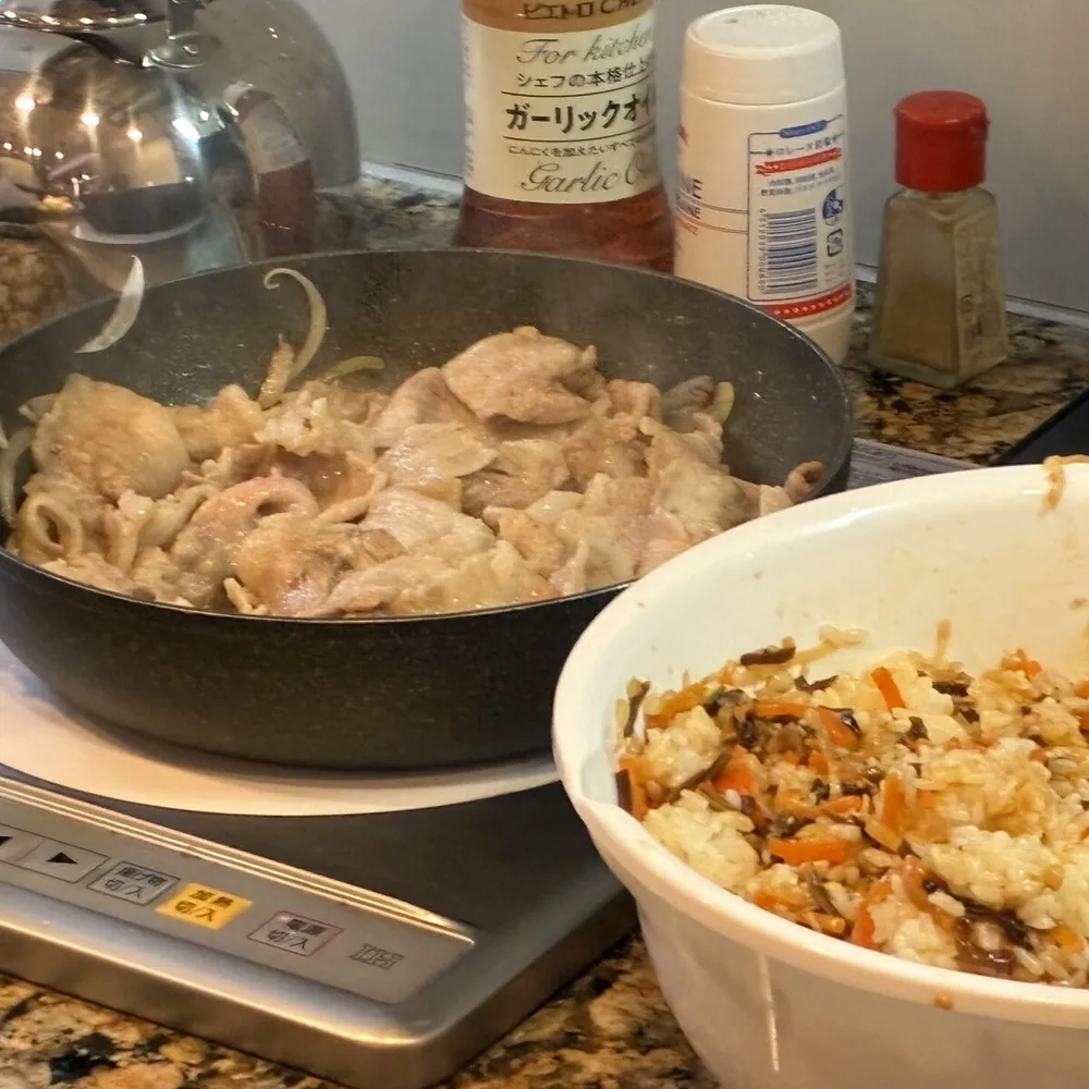 フライパンの豚肉の炒め物と、大きな器に入った混ぜご飯