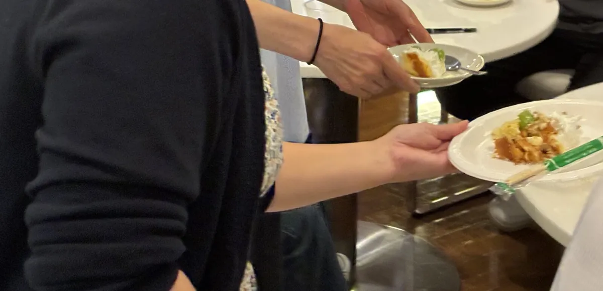 料理をのせたお皿を手渡す参加者の手元